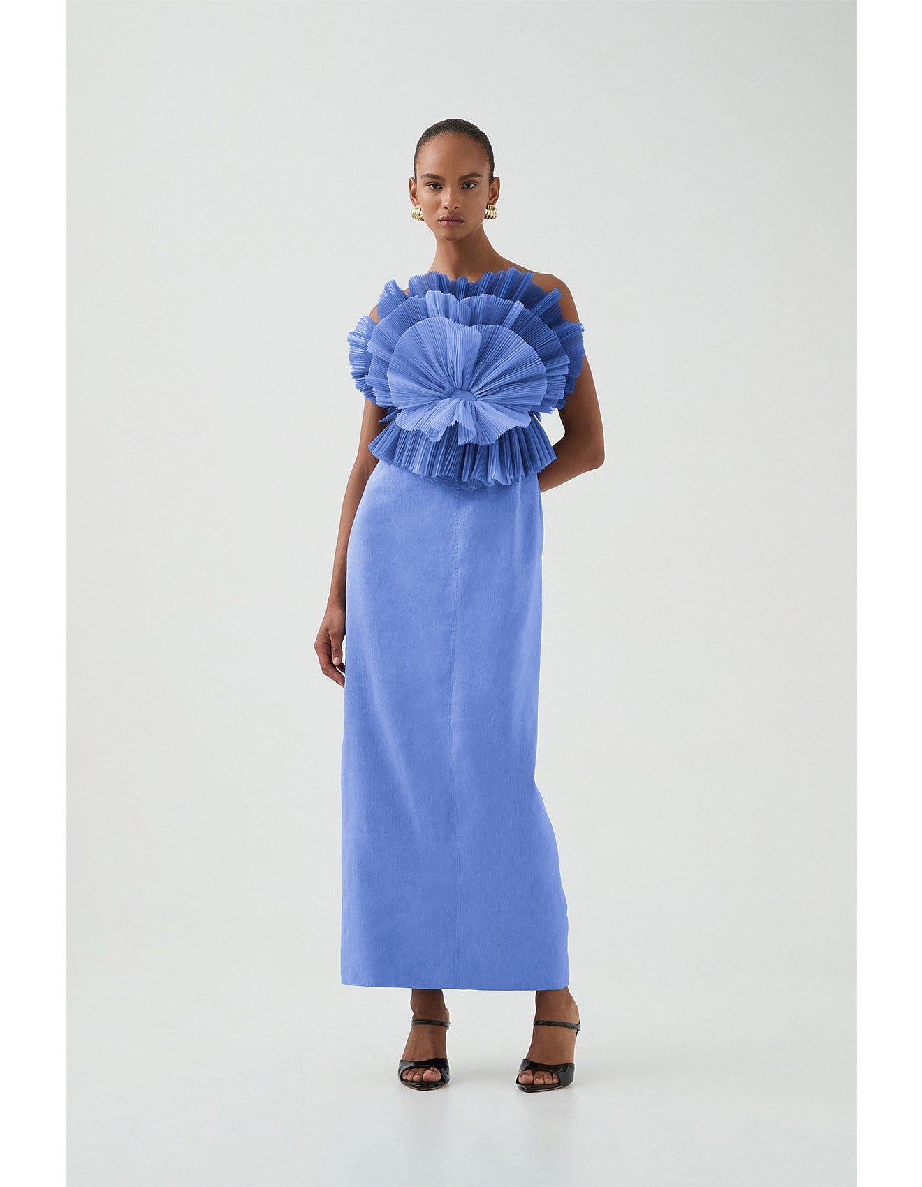 Woman wearing a blue aje dress with a ruffled top on a white background